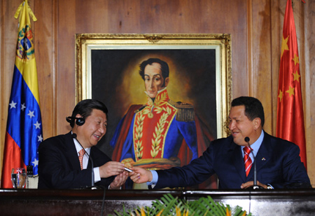 Chinese Vice President Xi Jinping (L) receives the first mobile phone produced jointly by China and Venezuela from Venezuelan President Hugo Chavez at a ceremony during which documents on bilateral collaboration between China and Venezuela in trade, finance, energy and agriculture sectors are signed, in Caracas, Venezuela, Feb. 18, 2009.[Xinhua]