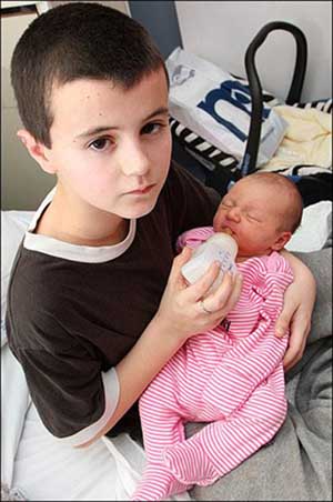  Alfie, a 13-year-old father bottle feeds his little daughter. [Xinhuanet/chinanews.com]