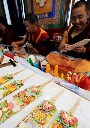 Tibetan lamas make colorful plates at a lama temple in Lhasa, capital of southwest China's Tibet Autonomous Region, Feb. 19, 2009. These plates are made from butter and will be inserted on Qiema, a two-tier rectangular wooden box containing roasted barley and food prepared with butter, parched barley meal and sugar. Local people are making preparation for the Tibetan New Year, which falls on Feb. 25. [Xinhua]