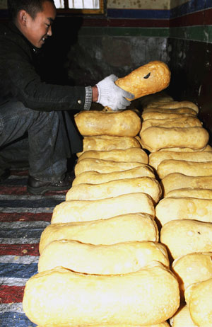 A Tibetan lama prepares a kind of traditional fried cake at a lama temple in Lhasa, capital of southwest China's Tibet Autonomous Region, Feb. 19, 2009. [Xinhua]