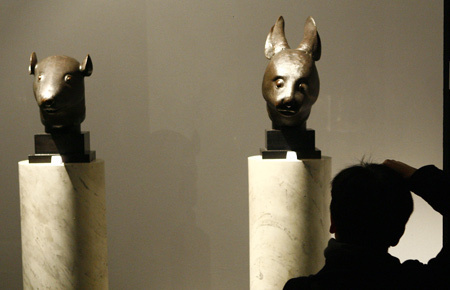 A photographer takes a picture of the Chinese bronze rat head and rabbit head sculptures displayed on the preview of the auction of Yves Saint Laurent and Pierre Berge's art collection at the Grand Palais in Paris, France, Feb. 21, 2009. [Xinhua]