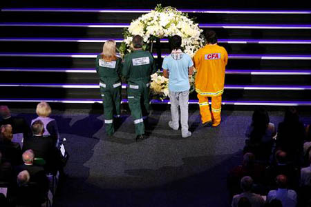 People lay flowers to the wreath during a memorial service for the national Day of Mourning at Rod Laver Arena in Melbourne, Australia, Sunday, Feb. 22, 2009, for the tragic events of the Victorian wildfires that killed more than 200 people.[Xinhua//AFP]