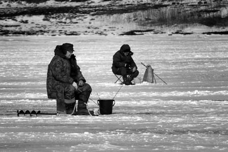 Local Russians sit on the ice to fish near the harbor of Russian's far east city Nakhodka Feb. 22, 2009. Local people have the habbit to go ice fishing in winter.[Xinhua]