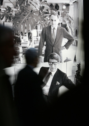 Visitors walk past the picture of late French fashion designer Yves Saint Laurent (front) and his business partner Pierre Berge on the auction preview of their art collection at the Grand Palais in Paris, France, Feb. 21, 2009. [Zhang Yuwei/Xinhua]