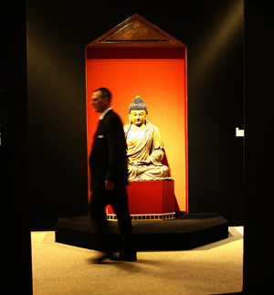 A staff member walks past a Chinese Buddhist joss displayed on the preview of the auction of Yves Saint Laurent and Pierre Berge's art collection at the Grand Palais in Paris, France, Feb. 21, 2009. [Zhang Yuwei/Xinhua]