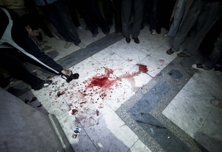 A photographer shoots bloodstain left in the blast scene located between the al-Hussein mosque and the Khan al-Khalili bazaar in Cairo, capital of Egypt, Feb. 22, 2009. [Zhang Ning/Xinhua]