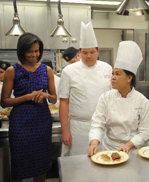 U.S. first lady Michelle Obama talks with White House executive chef Cristeta Comerford (C) and pastry chef William Yosses (R) as she gives a dinner preview for Sunday's Governors dinner at the White House in Washington February 22, 2009. [Xinhua/AFP]