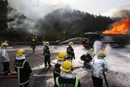 Firemen attempt to extinguish fire at the wreckage of an oil truck that self-ignited on the Dongguan-Shenzhen Expressway in south China's Guangdong Province, Feb. 23, 2009.[Xinhua]