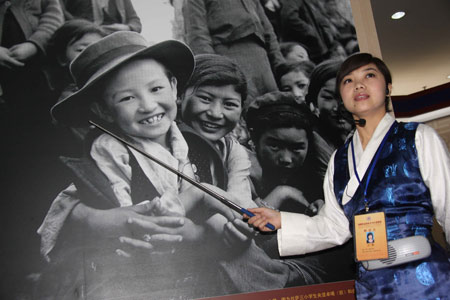 A guide introduces a photo in an exhibition marking the 50th anniversary of the Democratic Reform in Tibet Autonomous Region in Beijing, China, Feb. 24, 2009. [Xinhua]