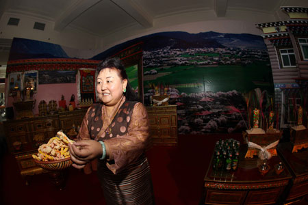  A Tibetan woman greets visitors in an exhibition marking the 50th anniversary of the Democratic Reform in Tibet Autonomous Region in Beijing, China, Feb. 24, 2009. [Xinhua]