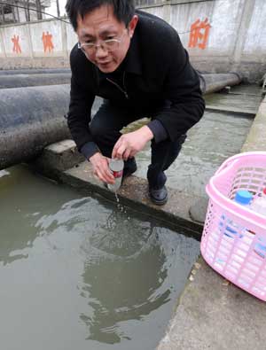 A staff member takes bottles of water for tests from the entrance to the contaminated water plant after it resumed operations in west Yancheng City, east China's Jiangsu Province, on Feb. 23, 2009. [Xinhua] 