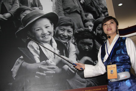 A guide introduces a photo in an exhibition marking the 50th anniversary of the Democratic Reform in Tibet Autonomous Region in Beijing, China, Feb. 24, 2009. [Xinhua] 