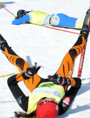 Skiers rest themselves on the ground after crossing the finish line during the women's Pursuit without a break of Cross-Country skiing in the 24th World Winter Universiade at the Yabuli Ski Resort 195km southeast away from Harbin, capital of northeast China's Heilongjiang Province, Feb. 23, 2009. 