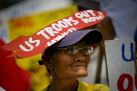 A woman, with a banner reading 'US Troops Out Now' on her hat, takes part in a rally in Manila, capital of the Philippines, Feb. 24, 2009.