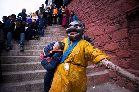 A monk plays with a child during the Lamaist devil dance ceremony at Tsurpu Monastery, about 70 kilometers of Lhasa, capital of southwest China's Tibet Autonomous Region, Feb. 23, 2009.[Liu Jie/Xinhua]