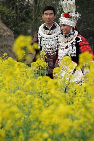 A young ethnic Miao couple in traditional attire walk around at Pingdiying Village of Shibing County in southeast of southwest China's Guizhou Province, Feb. 23, 2009. Local people held celebrations of traditional 'Sisters Festival' on Feb. 22-23, regarded as 'Saint Valentine's Day of Miao nationality', an occasion for young people to express love towards each other. [Feng Li/Xinhua]