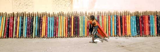 A worker carries saris for drying at a cotton sari factory in the southern Indian city of Hyderabad February 24, 2009.[Xinhua/Reuters]