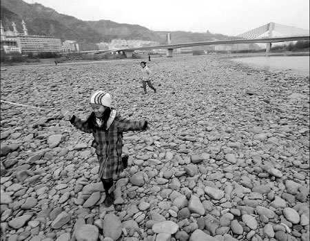 Children play on the parched riverbed of a section of the Yellow River in Lanzhou, Gansu Province, yesterday. [Chen Mingzhe/China Daily] 