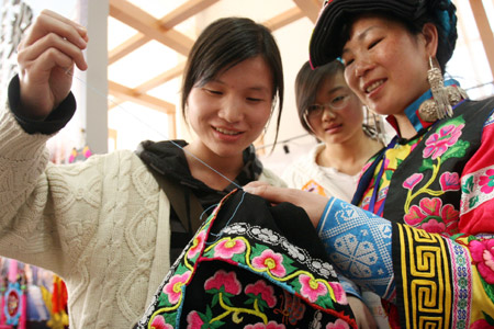 A girl (L) learns skills on embroidery from a woman of Qiang ethnic group at an exhibition of China's intangible cultural heritage in Beijing, China, Feb. 22, 2009.(Xinhua/Chen Xiaogen)