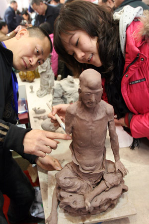 A girl learns how to make sculpture from a sculptor named Huang Zhiwei (L) at an exhibition of of China's intangible cultural heritage in Beijing, China, Feb. 22, 2009. (Xinhua/Chen Xiaogen) 