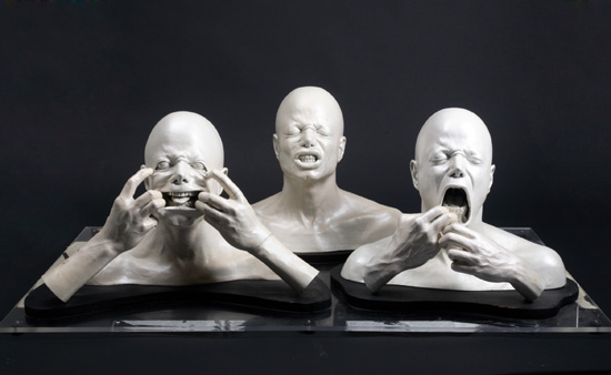 A group of three busts of Michael Jackson, two including forearms and hands, making faces. 