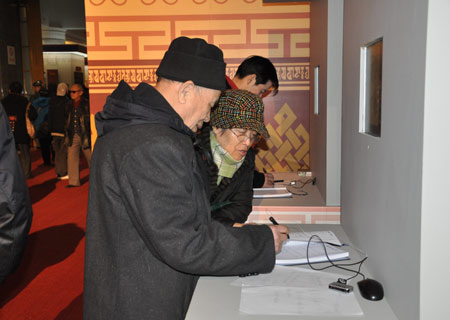 Zhang Chengzhou leaves message on a notebook as his wife looks on after visiting an exhibition marking the 50th anniversary of the Democratic Reform in Tibet Autonomous Region in Beijing, Feb. 25, 2009. (Xinhuanet Photo)
