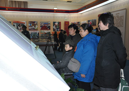 Visitors read an electronic book on the history of Tibet at an exhibition marking the 50th anniversary of the Democratic Reform in Tibet Autonomous Region in Beijing, Feb. 25, 2009. (Xinhuanet Photo) 