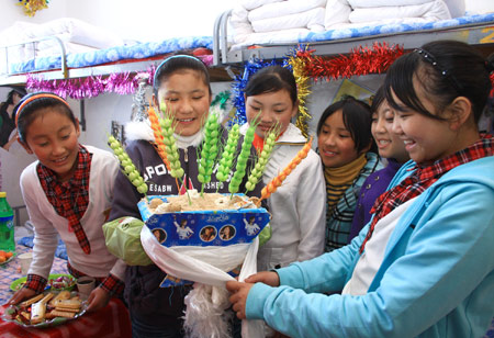 Students of Tibetan ethnic group decorate Qiema, a rectangular wooden box containing roasted barley, and highland barley, which symbolizing great harvest for the coming new year at Liaoyang First High School in north China's Liaoning Province on Feb. 25, 2009. Tibetans across China are celebrating the 50th Tibetan New Year after the Democratic Reform with their old traditions. (Xinhua/Cao Jingyi)