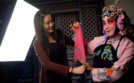 A lady (R), with her dressing and face-painting in Beijing Opera style, poses for pictures at a studio in the provincial city of Jinan, east China's Shandong Province, Feb. 25, 2009. Costume and face-painting in Beijing Opera style attracted more and more fans and youth to the studio for taking a series of memorial pictures. (Xinhua/Zhao Xiaoming)