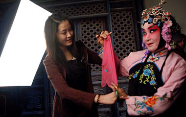 A lady (R), with her dressing and face-painting in Beijing Opera style, poses for pictures at a studio in the provincial city of Jinan, east China's Shandong Province, Feb. 25, 2009. Costume and face-painting in Beijing Opera style attracted more and more fans and youth to the studio for taking a series of memorial pictures.