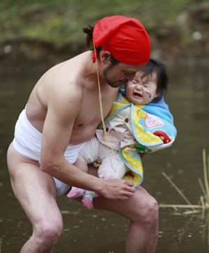 A father smears mud on his kid during a traditional 'Mud Festival' ceremony in the rice field on the outskirts of Yotsukaido City, Chiba prefecure, suburban Tokyo, Japan, on Feb. 25, 2009.