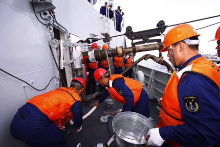 Soldiers on China's destroyer 'Guangzhou' deal with supplies from the comprehensive supply vessel 'Nancang', on the South China Sea, south China, Feb. 24, 2009. 