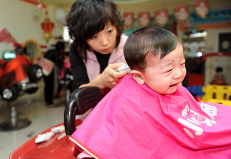 A hairdresser cuts hair for a child at a children hairdressing shop in Qingdao, east China's Shandong Province, Feb. 26, 2009. The day is the second day of the second month according to the lunar calender. It is believed in China that cutting hair on the day will bring good luck.