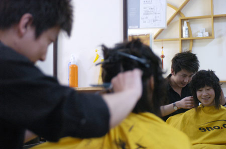 A hairdresser cuts hair for a customer at a hairdressing shop in Changchun, northeast China's Jilin Province, Feb. 26, 2009. The day is the second day of the second month according to the lunar calender. It is believed in China that cutting hair on the day will bring good luck.