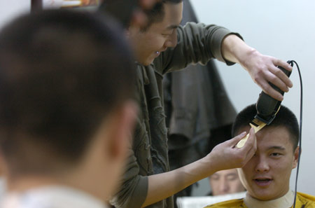 A hairdresser cuts hair for a customer at a hairdressing shop in Changchun, northeast China's Jilin Province, Feb. 26, 2009. The day is the second day of the second month according to the lunar calender. It is believed in China that cutting hair on the day will bring good luck.