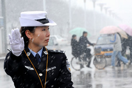 A traffic policewoman works in snow in Xi'an, capital of northwest China's Shaanxi Province, Feb. 26, 2009. Majority of Shaanxi Province witnessed the first snow of this spring on Thursday. [Tao Ming/Xinhua] 