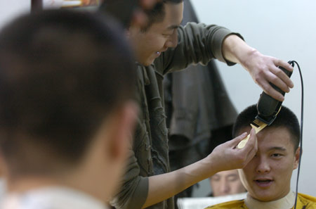A hairdresser cuts hair for a customer at a hairdressing shop in Changchun, northeast China&apos;s Jilin Province, Feb. 26, 2009. The day is the second day of the second month according to the lunar calender. It is believed in China that cutting hair on the day will bring good luck.