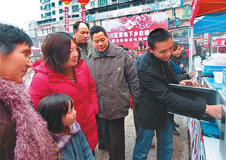 A shop clerk demonstrates the functions of a microwave oven to potential customers from the rural areas in Yongchuan, Chongqing. [China Daily]