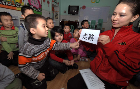A teacher of Uygur ethnic group teaches Chinese characters to children at a kindergarten in Urumchi, capital of northwest China's Xinjiang Uygur Autonomous Region, Feb. 26, 2009. This kindergarten offers bilingual education to pre-primary school children of local Uygur people. [Xinhua]