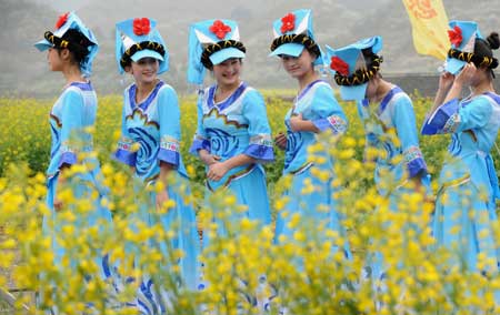 Some girls of the Bouyei ethnic group step into the rape field for performance on the opening ceremony of 'Golden Sea and Snow Mountains' tourist promoting campaign held in Guiding, a county of southwest China's Guizhou Province, March 1, 2009.