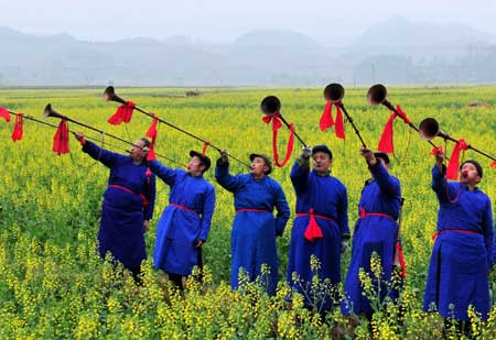 People of the Bouyei ethnic group play the trombone in the rape field on the opening ceremony of 'Golden Sea and Snow Mountains' tourist promoting campaign held in Guiding, a county of southwest China's Guizhou Province, March 1, 2009.