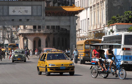 A taxi runs behind a trike in Havana, Cuba, Feb. 28, 2009. In Havana, weckers, trikes, carriages along with buses and taxis compose the city's main public transportation system. These vehicles witnessed the city's development and change.