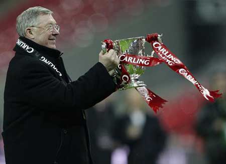 Manchester United's manager Alex Ferguson celebrates with the trophy after beating Tottenham Hotspur in their English League Cup final soccer match at Wembley Stadium in London March 1, 2009.