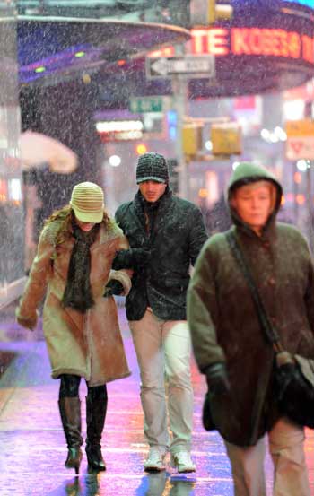 Pedestrians walk in snow at Times Square in New York, the United States, on March 1, 2009. A historical heavy snow in March fell in New York on Sunday.