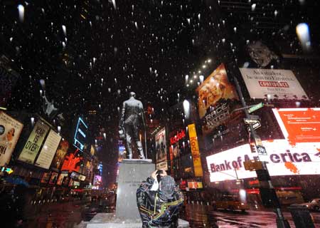 A man takes photographs in snow at Times Square in New York, the United States, on March 1, 2009. A historical heavy snow in March fell in New York on Sunday.