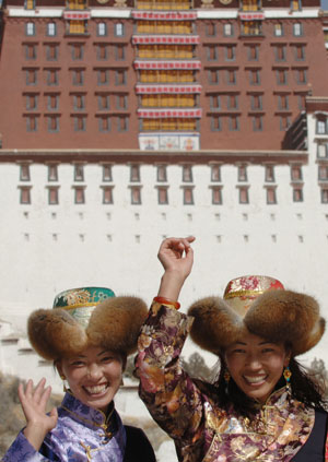 Two women pose for photos in front of the Potala Palace in Lhasa, capital of southwest China