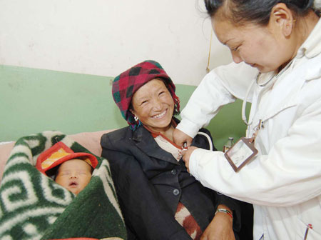 A woman (L) receives medical checkup at a hospital in Dagze County, southwest China