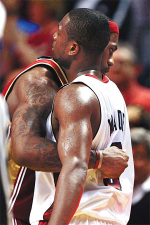 Cleveland Cavaliers forward LeBron James (left) and Miami Heat guard Dwyane Wade embrace after their NBA game in Miami on Monday. The Cavs won 107-100. [AP] 