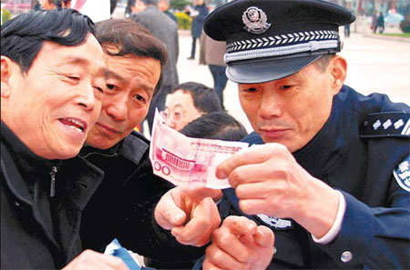 A police officer teaches citizens how to detect fake bank notes in Zhenjiang, Jiangsu province, on Feb 24. Feng Bo