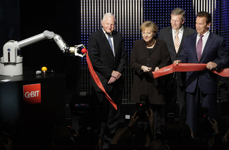 Intel Chairman Craig Barrett (L-R), German Chancellor Angela Merkel, Lower Saxony Premier Christian Wulff and California Governor Arnold Schwarzenegger cut the ribbon with robot Marvin during the opening ceremony of the CeBIT computer fair in the northern German town of Hanover March 2, 2009.